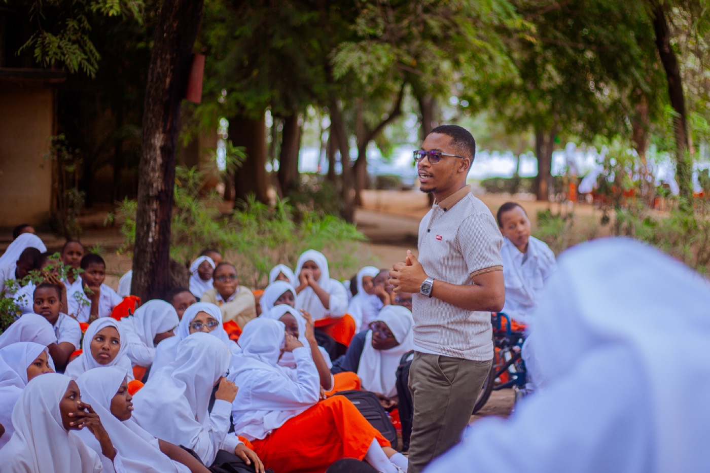 A GROW team member speaks with students seated in the schoolyard