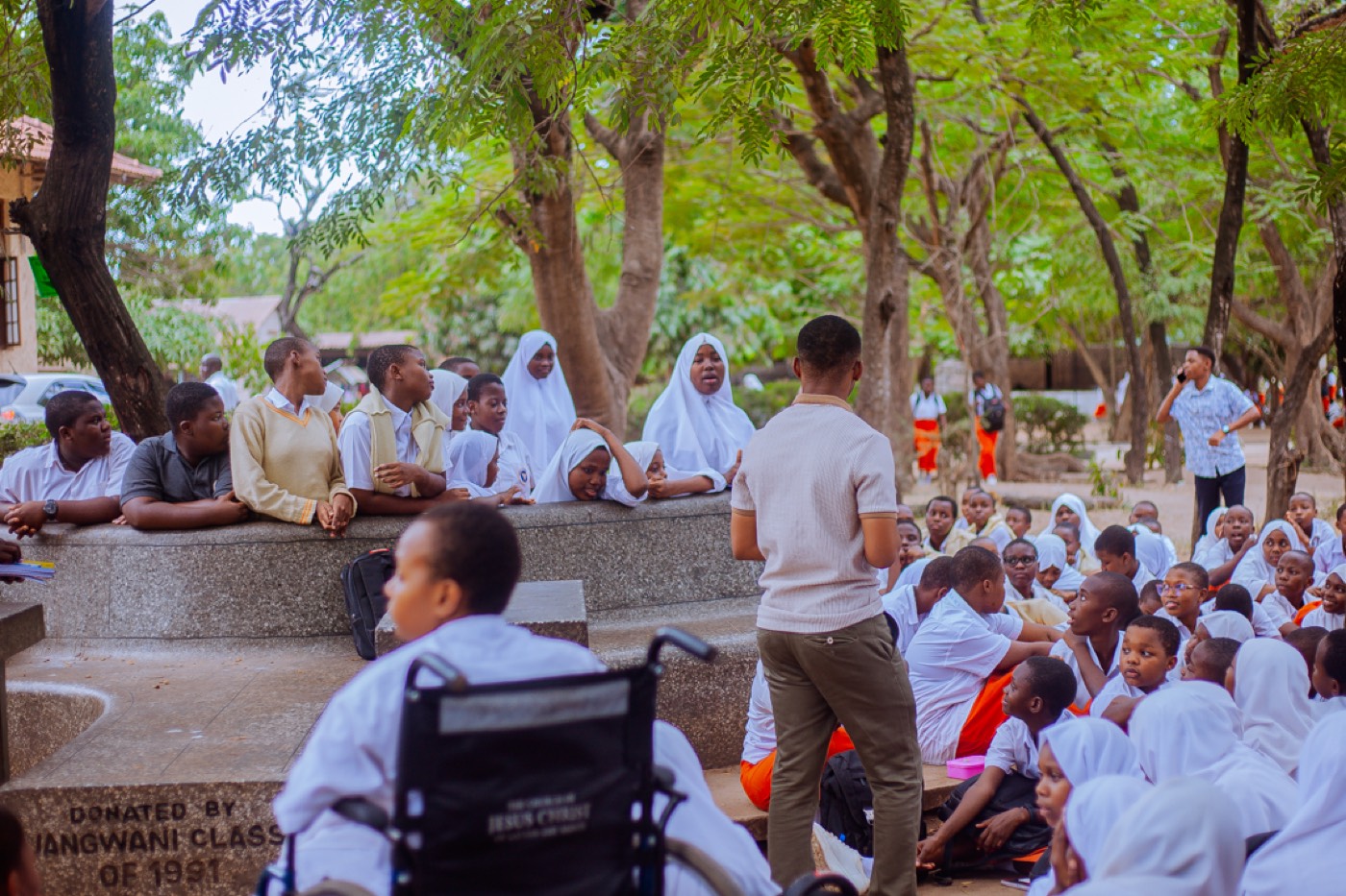 A GROW educator speaks with students gathered close by, including a student using a wheelchair