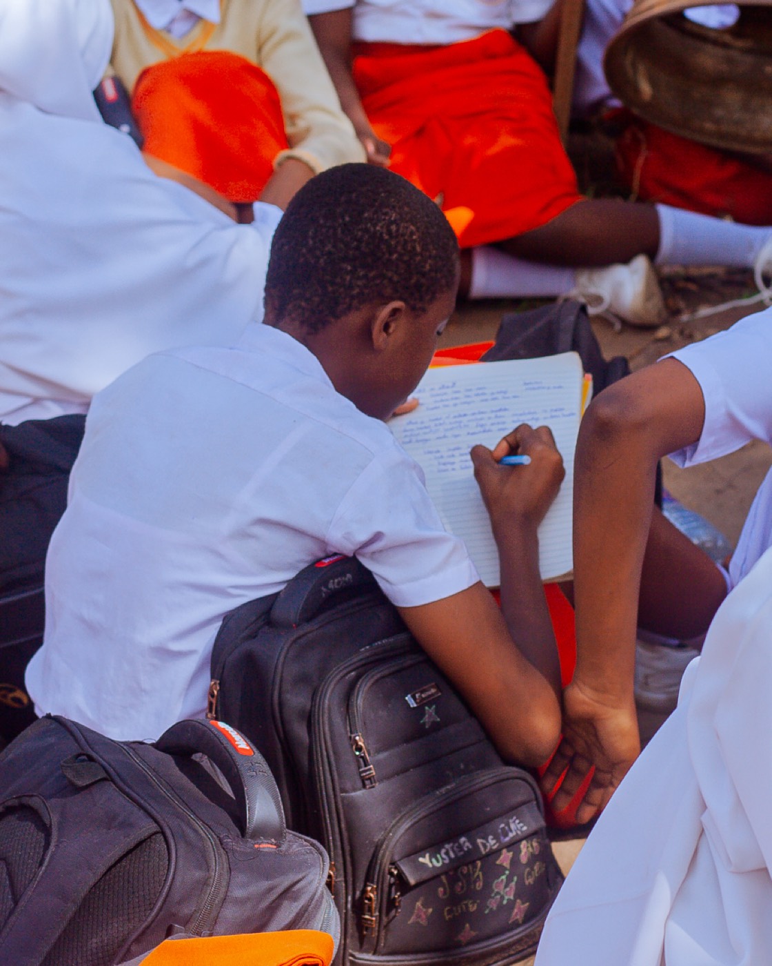 A student takes notes surrounded by classmates