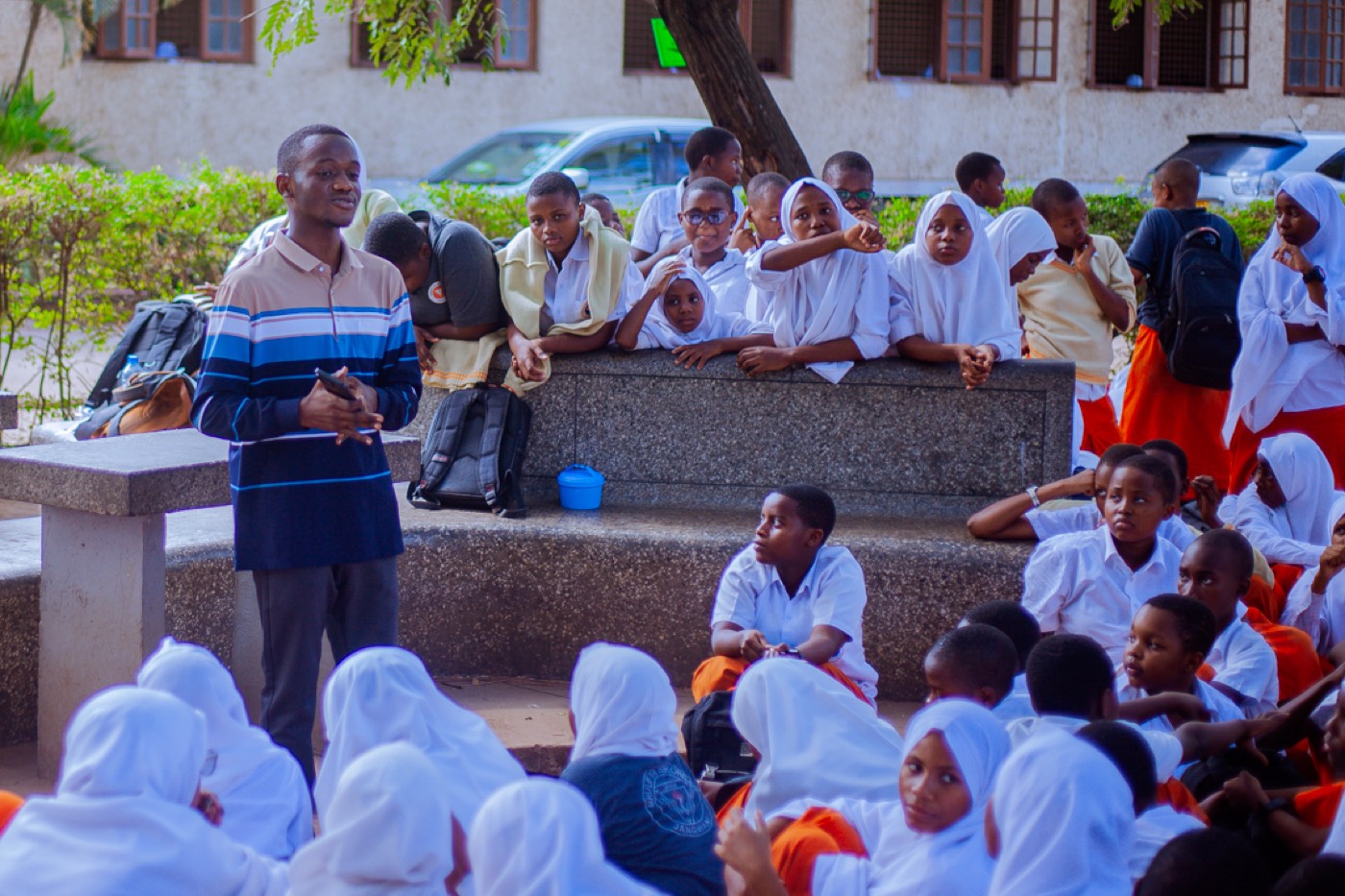 A GROW educator addresses students seated together outdoors